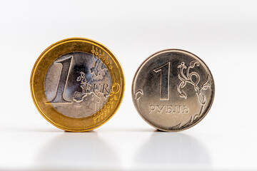 Pièces de 1 euro et de 1 rouble sur fond blanc. Concepts de taux de change, de transactions financières et d'échanges bancaires entre l'Union Européenne et la Fédération de Russie