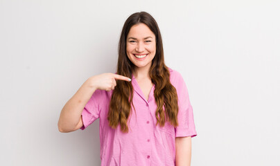 pretty caucasian woman looking happy, proud and surprised, cheerfully pointing to self, feeling confident and lofty