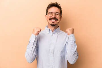 Wall Mural - Young caucasian man isolated on beige background celebrating a victory, passion and enthusiasm, happy expression.