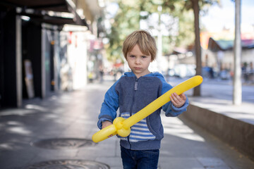 Sticker - Cute little child tourist, holding balloon made as a sword, admiring Barcelona city, family travel with kids