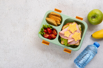 Wall Mural - Healthy school lunch box with sandwich and salad on the table. Banana, apple and a bottle of water. Back to school