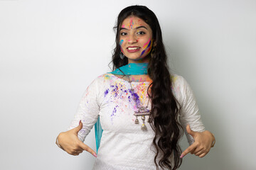 Wall Mural - Young indian girl with powder colours on her face for festival of colours Holi, a popular hindu festival celebrated across india, isolated over white background, selective focus advertisement pose