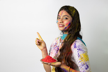 Wall Mural - Young indian girl holding plate of powder colours for festival of colours Holi, a popular hindu festival celebrated across india, isolated over white background, selective focus advertisement pose