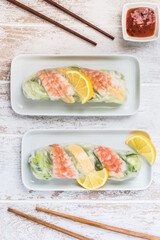 Two summer rolls with salad and prawns on a white wooden background, japanese, asian food. Top view.