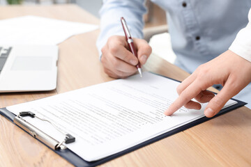 Poster - Businesspeople signing contract at wooden table, closeup