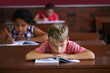 © Mapodile M/peopleimages.com - School sucks. A young boy resting his head on his arms as he sits in a classroom looking bored.
