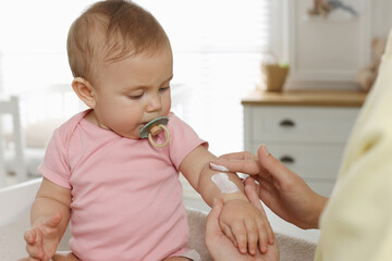 Canvas Print - Mother applying body cream on her little baby at home, closeup