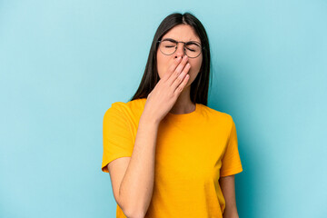 Young caucasian woman isolated on blue background yawning showing a tired gesture covering mouth with hand.