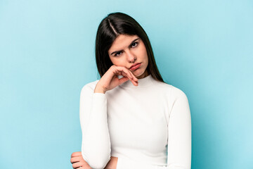 Young caucasian woman isolated on blue background tired of a repetitive task.