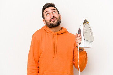 Wall Mural - Young caucasian man holding an iron isolated on white background dreaming of achieving goals and purposes