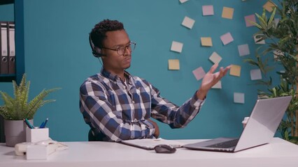 Wall Mural - young man talking with client on phone call at helpline call center, using headset with microphone t