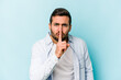 © Asier - Young caucasian man isolated on blue background keeping a secret or asking for silence.