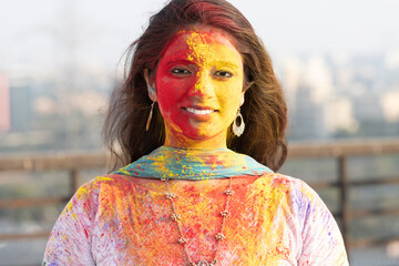 Wall Mural - Pretty Young indian smart girl with face coloured with gulal for festival of colours Holi, a popular hindu festival celebrated across india