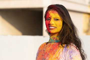 Wall Mural - Pretty Young indian smart girl with face coloured with gulal for festival of colours Holi, a popular hindu festival celebrated across india