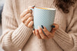© svetograph - A girl in a beige sweater with a blue mug in her hands. Blue porcelain mug mockup for your design