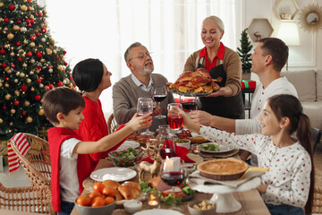 Canvas Print - Happy family clinking glasses of drinks at festive dinner indoors. Christmas celebration