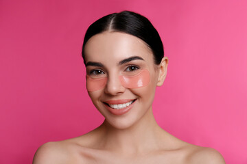 beautiful young woman with under eye patches on pink background