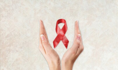 Sticker - Female hands with red ribbon symbol of aids awareness on background