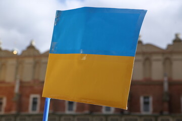 Wall Mural - Ukrainian flag aginst historical building in Krakow city center during street demonstration to support Ukraine against Russia aggression