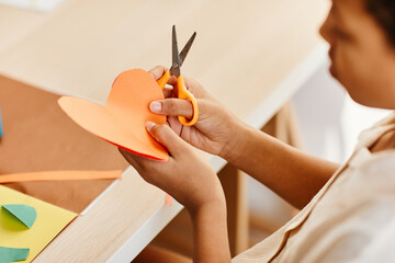 Minimal close up of young girl holding paper heart while making handmade holiday card