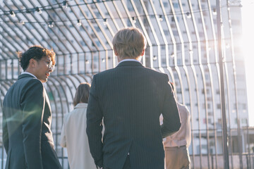 Group of business people walking in business district. Young men and women talking and discussing outdoors