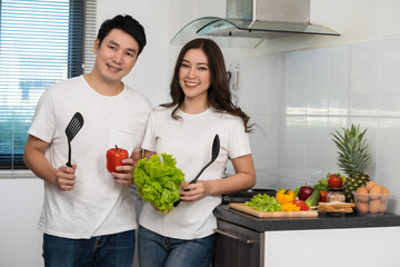 Wall Mural - couple cooking and preparing vegetables in the kitchen at home