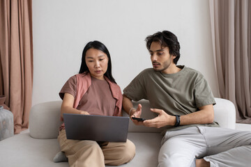 Aufkleber - Two intercultural employees discussing online information on laptop screen while Asian female explaining points of presentation