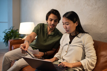 Aufkleber - Young confident businessman explaining his Asian female colleague online data while pointing at laptop screen with pencil