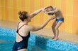 © ninelutsk - Toddler child learning to dive in indoor swimming pool with teacher. Standing on side, balancing and general physical activity for kids in water, early development. Boy kid instructed