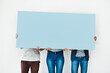 © Arnéll K/peopleimages.com - Your space with a bit of blue. Studio shot of a group of people covering themselves with a blank placard against a white background.