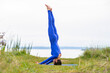 © Pelo Blanco Photo - Athletic woman doing yoga in a grass field overlooking a body of water.