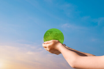 Canvas Print - child hands holding green earth globe over blurred sunset sky background. world environment day conc