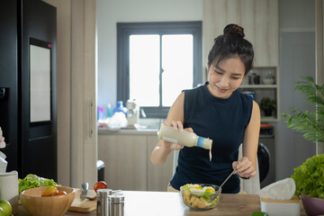 Wall Mural - Woman pouring sauce on salad in a glass bowl. Healthy food and diet nutrition.