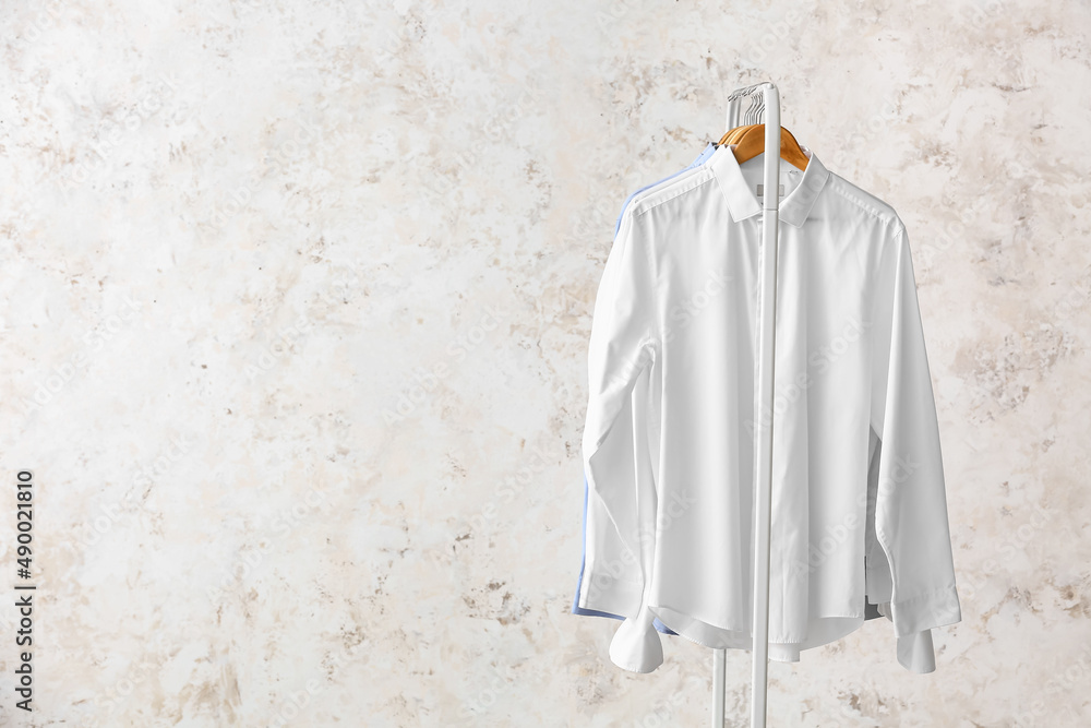 Rack with clean shirts on grunge background