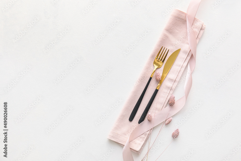 Elegant cutlery and lagurus flowers on light background