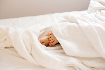 Wall Mural - Little toddler's feet, wrapped in a towel, kid lying in bed