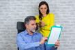 © Nenad - Business people discussing over clipboard in office. Real estate agent with client in office. Business People Discussion Teamwork Togetherness Concept.