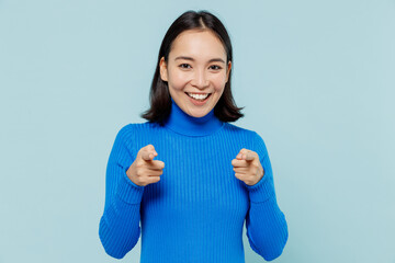 Wall Mural - Charismatic happy young woman of Asian ethnicity 20s years old wear blue shirt pointing index fingers camera on you motivating encourage isolated on plain pastel light blue background studio portrait