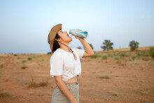 Woman Drinking Water In Desert Field