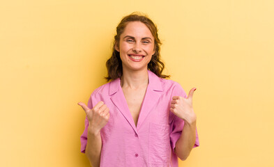 young pretty woman smiling joyfully and looking happy, feeling carefree and positive with both thumbs up