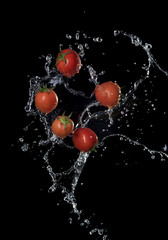Wall Mural - fresh red tomatoes in splash of water isolated on black background