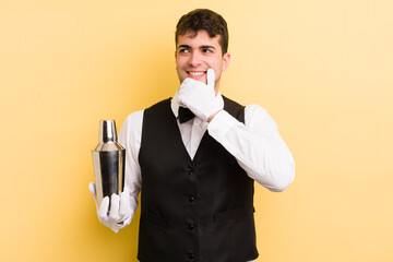 Wall Mural - young handsome man smiling with a happy, confident expression with hand on chin. bartender cocktail