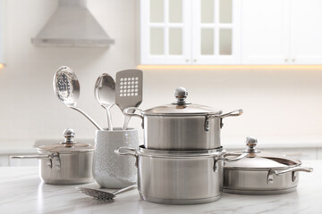 Poster - Set of stainless steel cookware and kitchen utensils on white table indoors