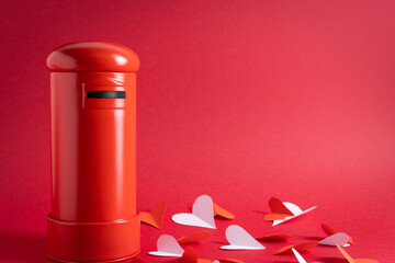 Wall Mural - Closeup of a red mailbox and white paper hearts on a red background for a valentine letters