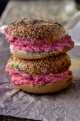 pink strawberry cream cheese spread onto sliced seeded bagel halves for bagel sandwiches