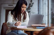 © chika_milan - A smiling female student is sitting in a coffee shop and studying.