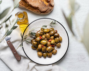 Canvas Print - Top view of pickled green olives in a white plate with olive branch and olive oil in a glass bottle