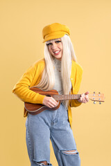 Sticker - Blonde woman in cap and yellow jacket smiling and playing ukulele on yellow background