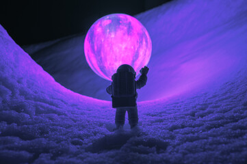 silhouette of the toy of astronaut against levitating glowing sphere over surface icy planet covered