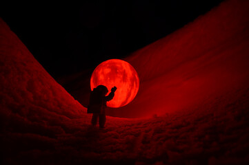 Wall Mural - silhouette of the toy of astronaut against levitating glowing sphere over surface icy planet covered